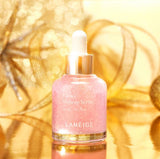 A bottle of Laneige Glowy Makeup Serum sits on a gold surface, its shimmering pink liquid and gold accents reflecting the festive background, promising a radiant and healthy glow for long-lasting makeup.